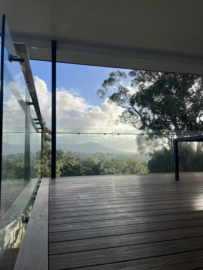 Elevated covered deck with a frameless glass balustrade looking out to the Illawarra escarpment