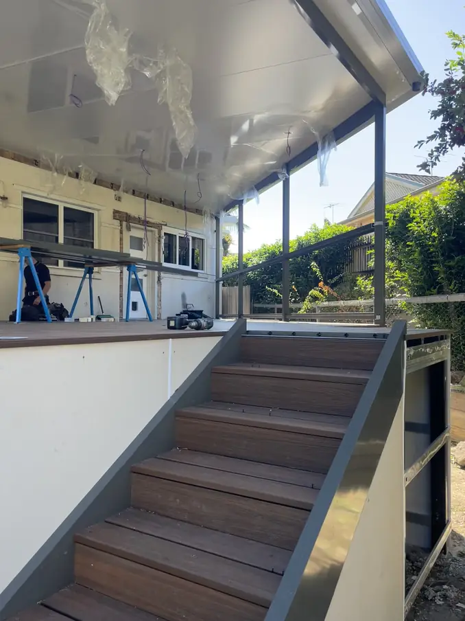 New deck stairs being built under a freshly installed patio roof